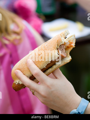 ENGLAND West Sussex Findon Village Sheep Fair Teenage girl holding hot dog with tomato ketchup and onions with bite taken out Stock Photo