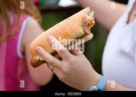 ENGLAND West Sussex Findon Village Sheep Fair Teenage girl holding hot dog with tomato ketchup and onions with bite taken out Stock Photo