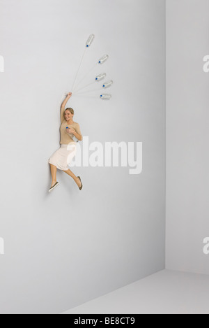 Woman held aloft by bunch of water bottles Stock Photo