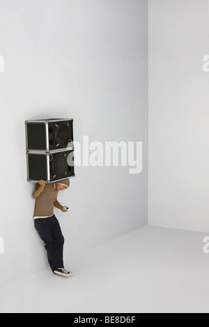 Man carrying two speakers on shoulders, looking down at cell phone in hand Stock Photo