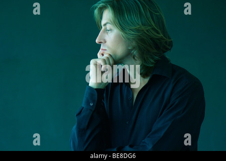 Man with hand under chin looking away Stock Photo