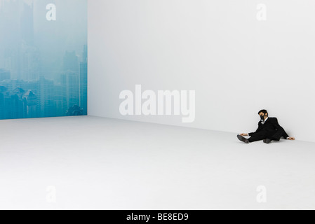 Businessman lying on floor, wearing gas mask, cityscape obscured by smog in background Stock Photo