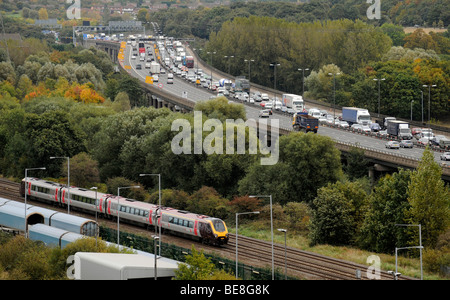 A  COMMUTER TRAIN RUNNING NEXT TO QUEUING TRAFFIC ON THE ELEVATED M6 MOTORWAY NORTHBOUND NEAR BIRMINGHAM ,UK Stock Photo