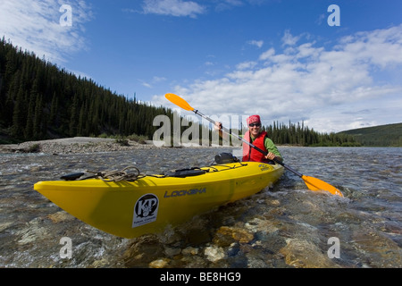 Young woman in kayak, paddling, kayaking, clear, shallow water of upper Liard River, Yukon Territory, Canada Stock Photo