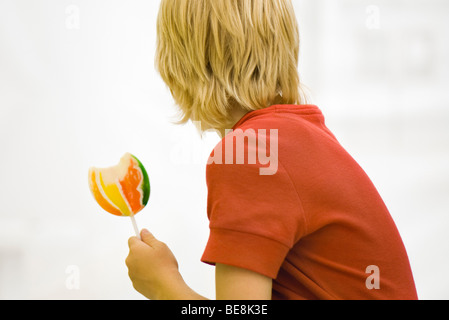 Boy holding lollipop looking away Stock Photo