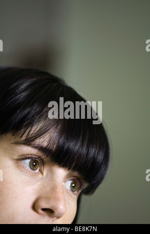 young woman looking up contemplatively with a forefinger at the mouth ...