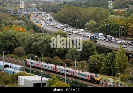 A  COMMUTER TRAIN RUNNING NEXT TO QUEUING TRAFFIC ON THE ELEVATED M6 MOTORWAY NORTHBOUND NEAR BIRMINGHAM ,UK Stock Photo