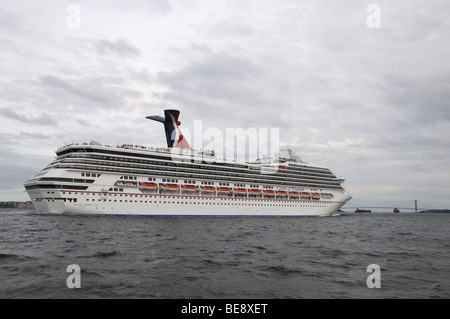 Passengers line the decks of Carnival Triumph as she leaves New York harbor. The Verrazano Narrows Bridge is in the background. Stock Photo