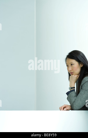 Businesswoman sitting with hand under chin, looking away, portrait Stock Photo