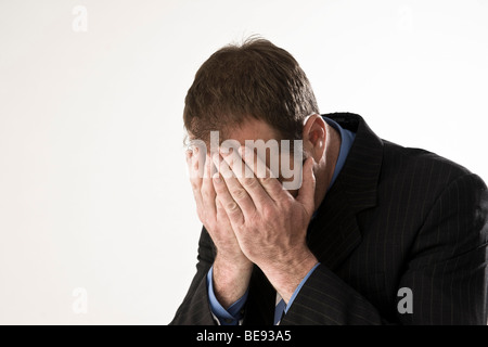 Man wearing a suit, hands covering his face Stock Photo