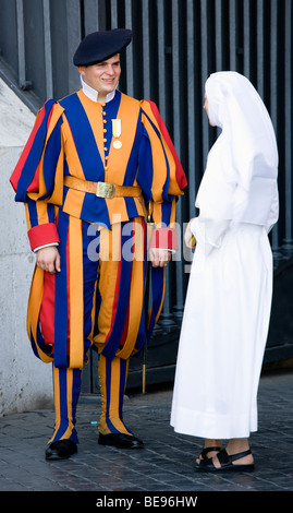 ITALY Lazio Rome Vatican City A Swiss Guard in full ceremonial uniform dress talking to a nun dressed in white. Stock Photo