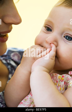 Mother holding infant with fingers in mouth