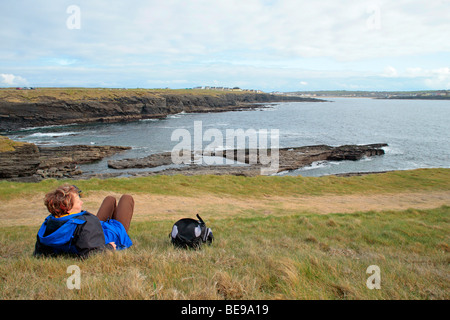 a young woman enjoying the view near Kilkee in County Clare at the West Coast of the Republic of Ireland Stock Photo