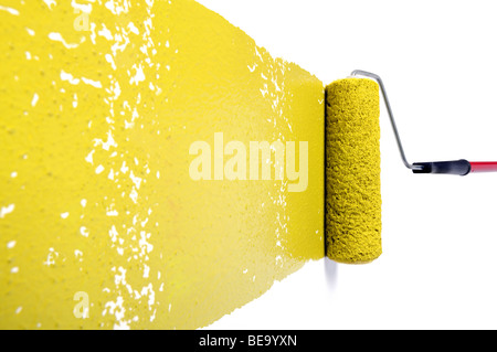 Pain roller with yellow paint on white wall Stock Photo