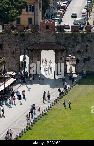 Tourists streaming though the Porta Nuova in Pisa entering the Campo dei Miracoli or field of Miracles with the Leaning Tower. Stock Photo