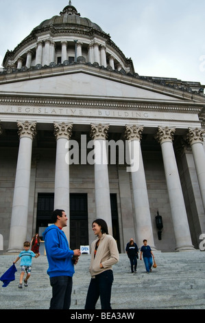 A young adult couple visits on the steps in front of the Washington State Capitol Legislative Building. Stock Photo