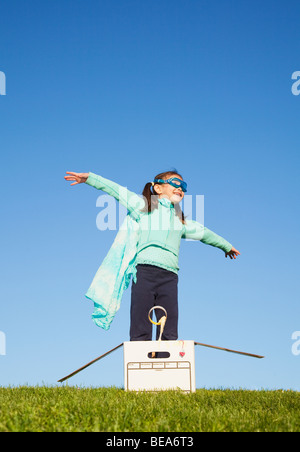 Mixed race girl wearing cape and standing in box Stock Photo