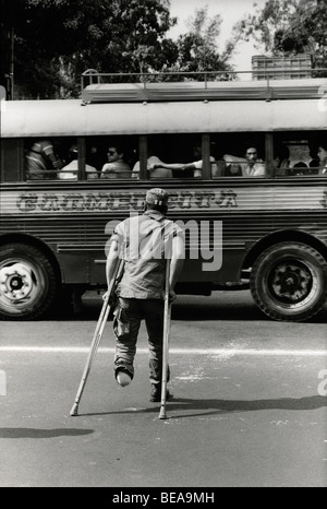 SAN SALVADOR, EL SALVADOR, MAY 1986: A Salvadoran soldier who has had a foot blown off by a mine crosses the road on crutches from the military hospital.   The F.M.L.N. guerillas are making increasing use of home-made plastic mines.   Photo by Mike Goldwater Stock Photo