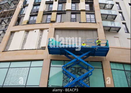 Using a scissor lift in facade cladding works after spraying the facade ...