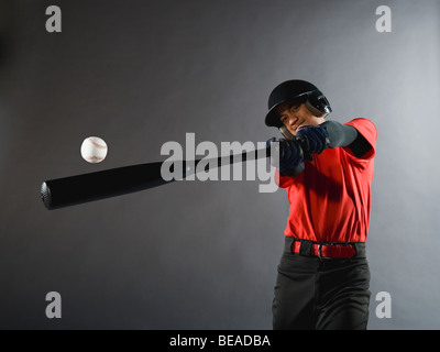 Mixed race baseball player swinging bat