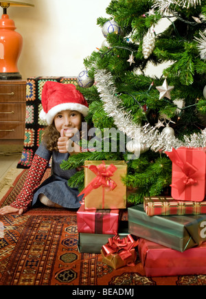 little girl with thumps up behind Christmas tree