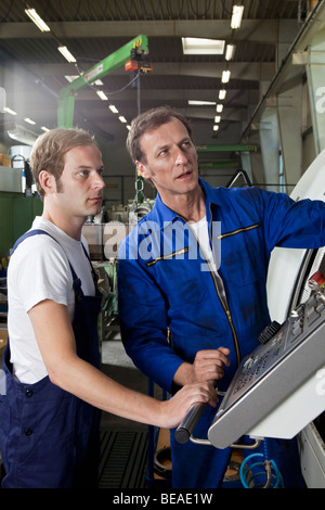 Two manual workers talking and working in a factory Stock Photo