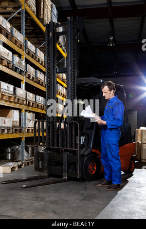 A manual worker looking at a checklist in a metal parts warehouse Stock Photo