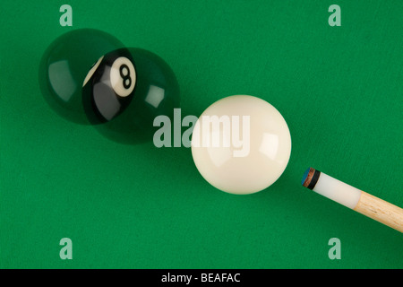 A pool cue, cue ball and eight ball on a pool table, multiple exposure Stock Photo