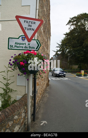 dh  ST MARTIN GUERNSEY Guernsey Filter in turn sign with flowers and car in filter box crossroad intersection Stock Photo