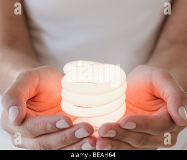 Woman holding glowing compact fluorescent bulb Stock Photo