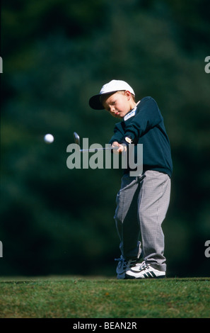 Junior golfer playing iron shot from tee during mini competition Stock Photo