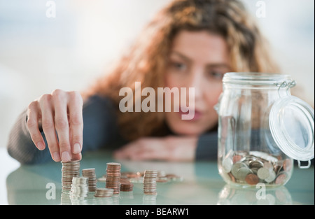 Hispanic woman counting coins from jar Stock Photo