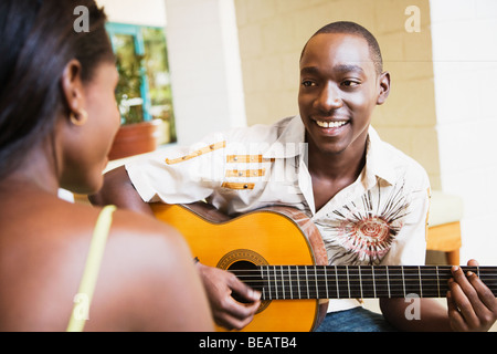 African man playing guitar for woman Stock Photo