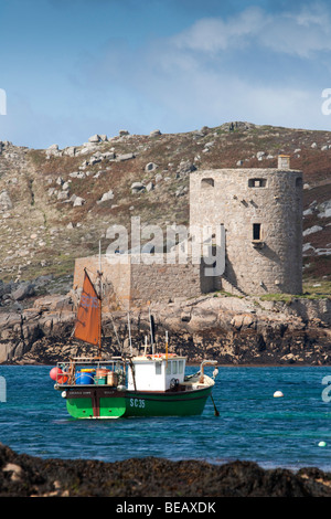 Cromwell’s Castle, Tresco, Isles of Scilly, viewed from Bryher, with  fishing boat in the foreground Stock Photo