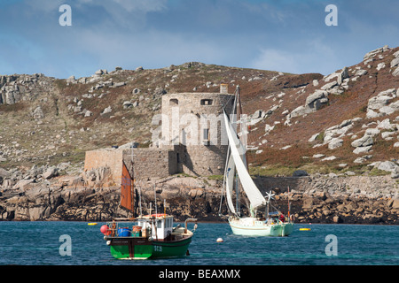 Cromwell’s Castle, Tresco, Isles of Scilly, viewed from Bryher, with yacht and fishing boat in the foreground Stock Photo