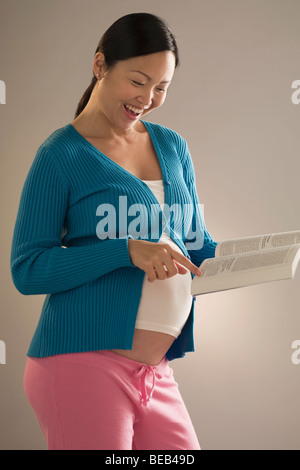Pregnant woman reading a book and smiling Stock Photo