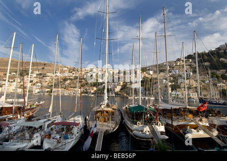 Yachts in Yialos harbour on the Greek Dodecanese island of Symi with the neo-classical houses of the town in the background. Stock Photo