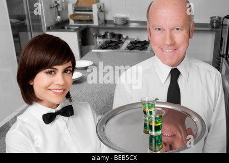 Waiter and a waitress standing in the kitchen and smiling Stock Photo