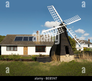 English cottage fitted with solar panels and old windmill England UK Stock Photo