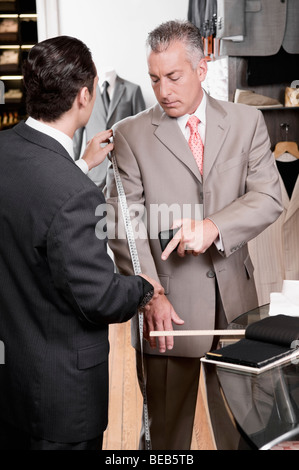 Tailor taking the measurements of a customer Stock Photo
