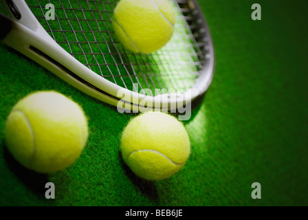 Close-up of three tennis balls with a tennis racket in a court Stock Photo