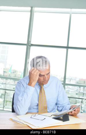 Businessman Reading Newspaper at His Desk in Office Setting Stock Photo