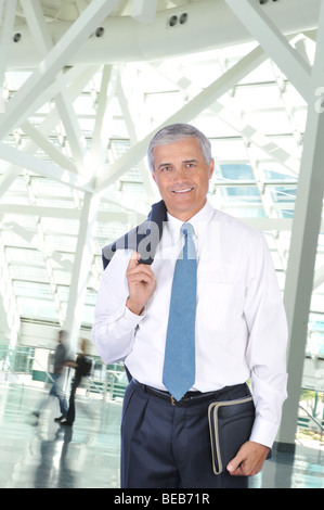 Standing Businessman with Jacket over his Shoulder in Building Lobby Stock Photo