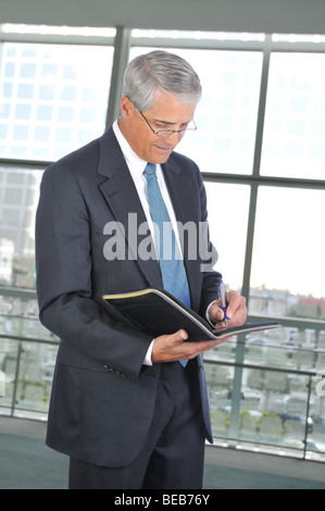 Standing Businessman Taking Notes in office building setting Stock Photo