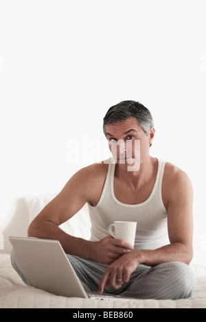 Portrait of a man working on a laptop on the bed Stock Photo