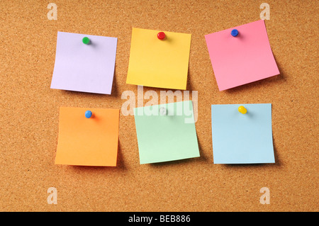 Adhesive notes of various colors pinned to cork surface Stock Photo