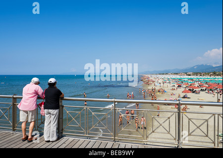 Elderly couple looking out over the beach from the pier at Marina di Pietrasanta, Tuscan Riviera, Tuscany, Italy Stock Photo