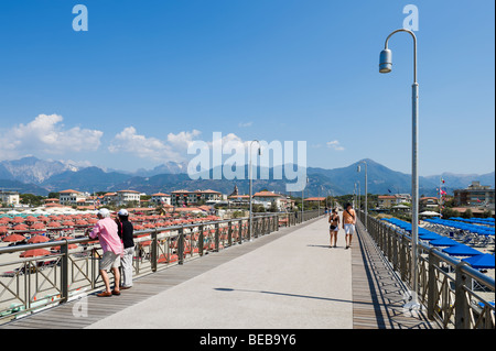 Elderly couple looking out over the beach from the pier at Marina di Pietrasanta with the town behind, Tuscan Riviera, Italy Stock Photo