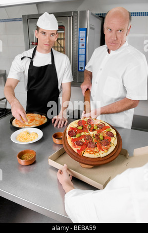 Three chefs preparing pizza in the kitchen Stock Photo