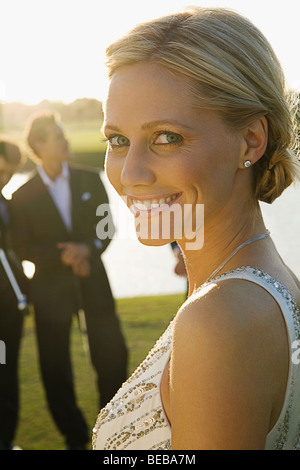 Portrait of a bride smiling with two golfers in the background, Biltmore Golf Course, Coral Gables, Florida, USA Stock Photo